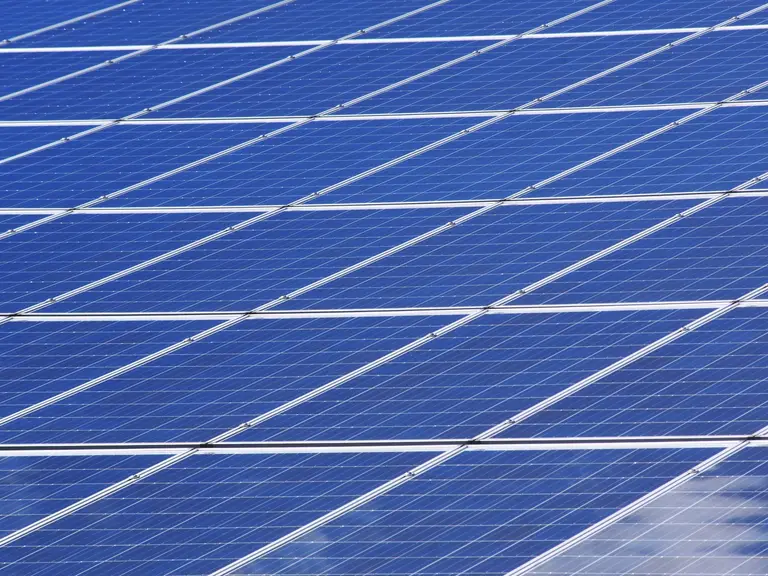Close-up diagonal view of a finished monocrystalline solar panel array against a blue sky
